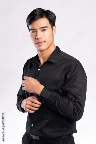 handsome confident young man standing and smiling in a back shirt. on white background.