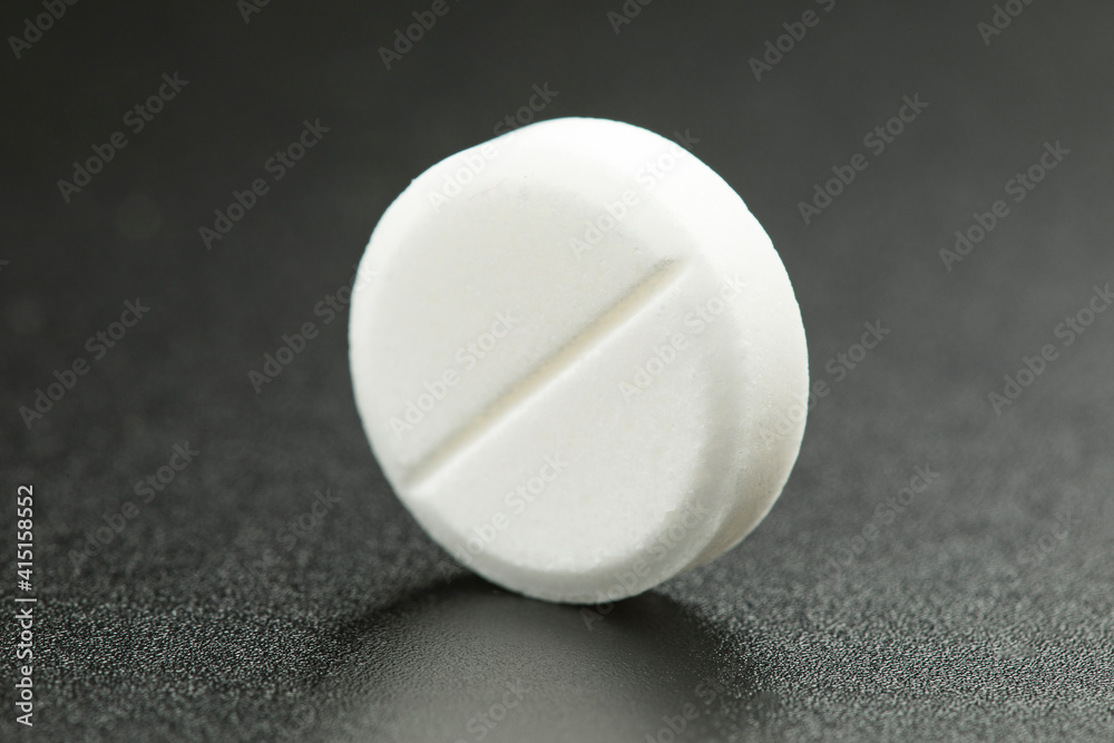White round pill on black background. Health care concept.