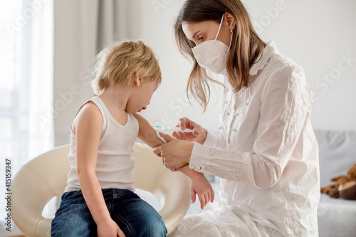 Little toddler boy, getting injection in consulting room from pediatrition photo