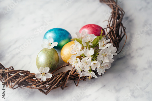 Easter wreath with dyed eggs and spring flowers flatlay