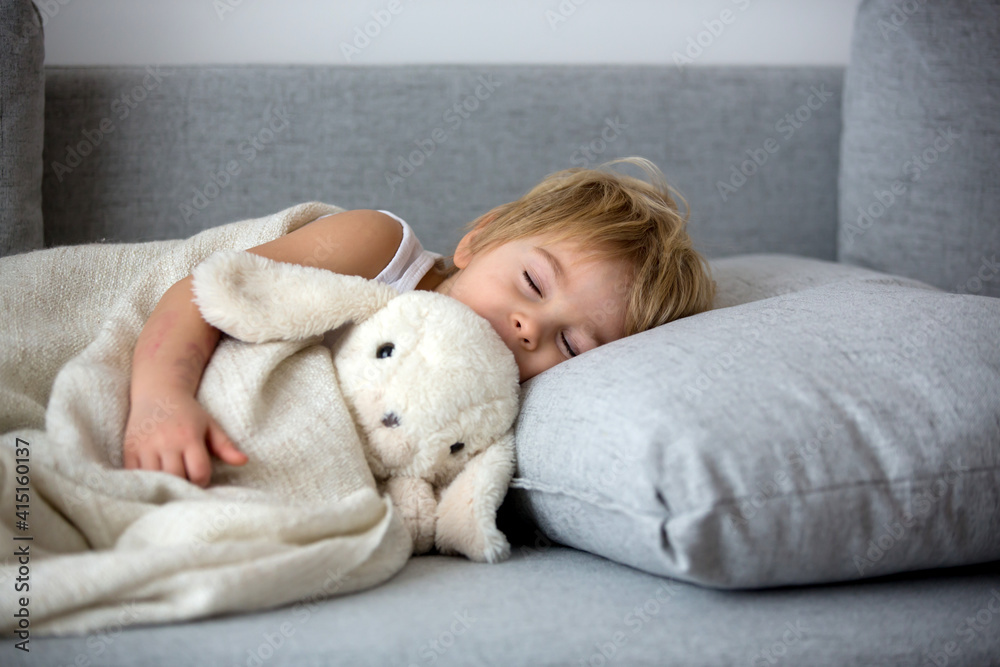 Blond toddler child, wiping his nose in a tissue, sneezing and coughing Blond toddler child, wiping his nose in a tissue, sneezing and coughing
