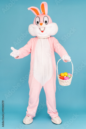 Fotografie, Obraz Easter bunny or rabbit or hare with basket of colored eggs, having fun, dancing, celebrates Happy easter
