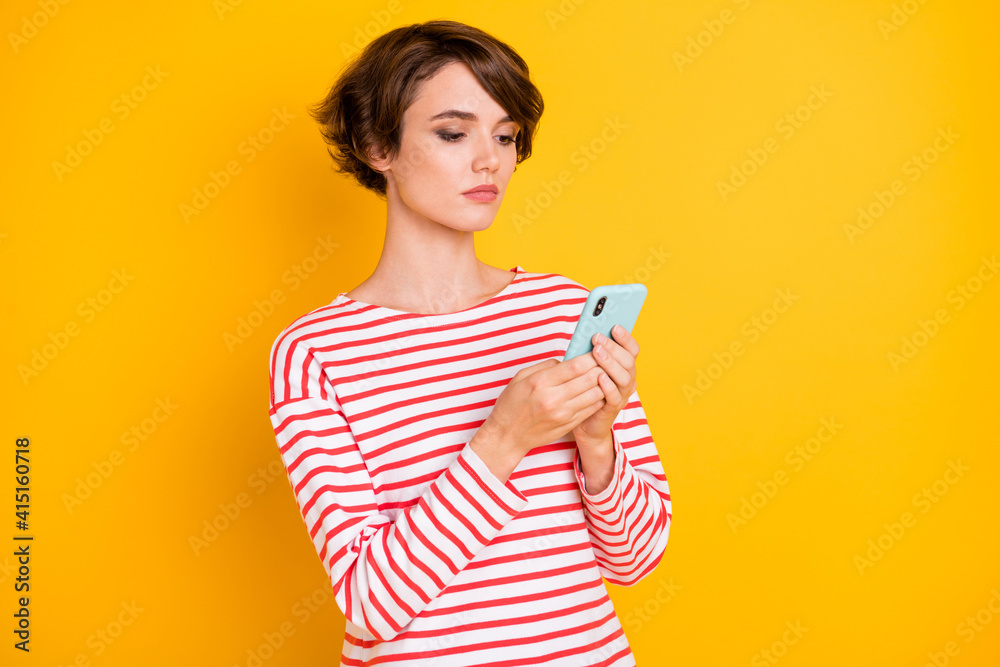 Portrait of serious brunette lady look telephone wear red shirt isolated on orange color background Portrait of serious brunette lady look telephone wear red shirt isolated on orange color background