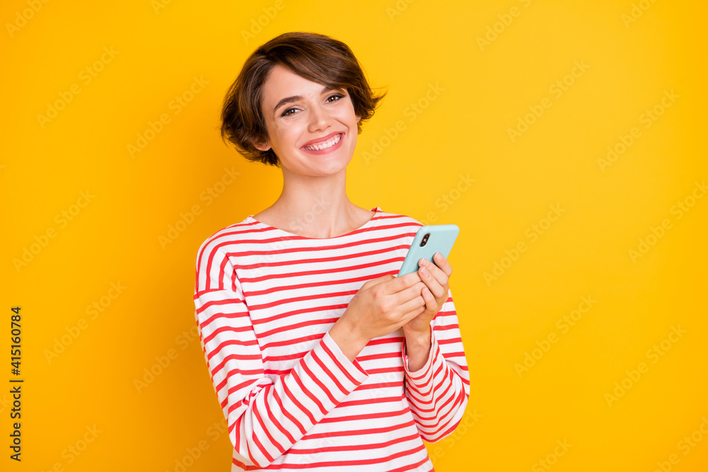 Portrait of young beautiful cheerful positive smiling girl blogger using smartphone isolated on yellow color background Portrait of young beautiful cheerful positive smiling girl blogger using smartphone isolated on yellow color background