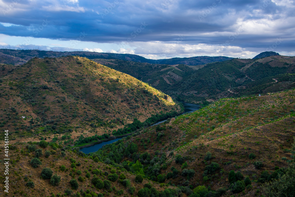 A la izquierda España, a la derecha Portugal: Frontera entre ambos países marcada por el río Duero en una imagen al atardecer con vegetación verde y nubes oscuras