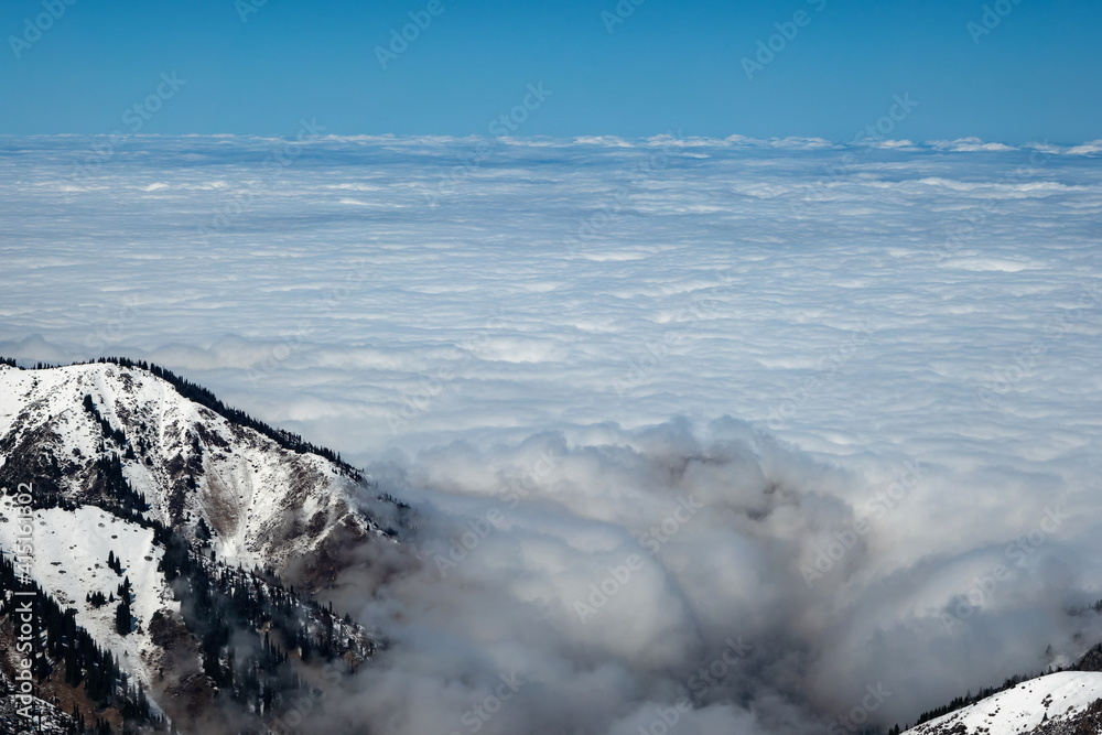 Mountain winter landscape. Higher than clouds. Mostly cloudy. Alma-Ata's region. Tien Shan mountains. Kazakhstan