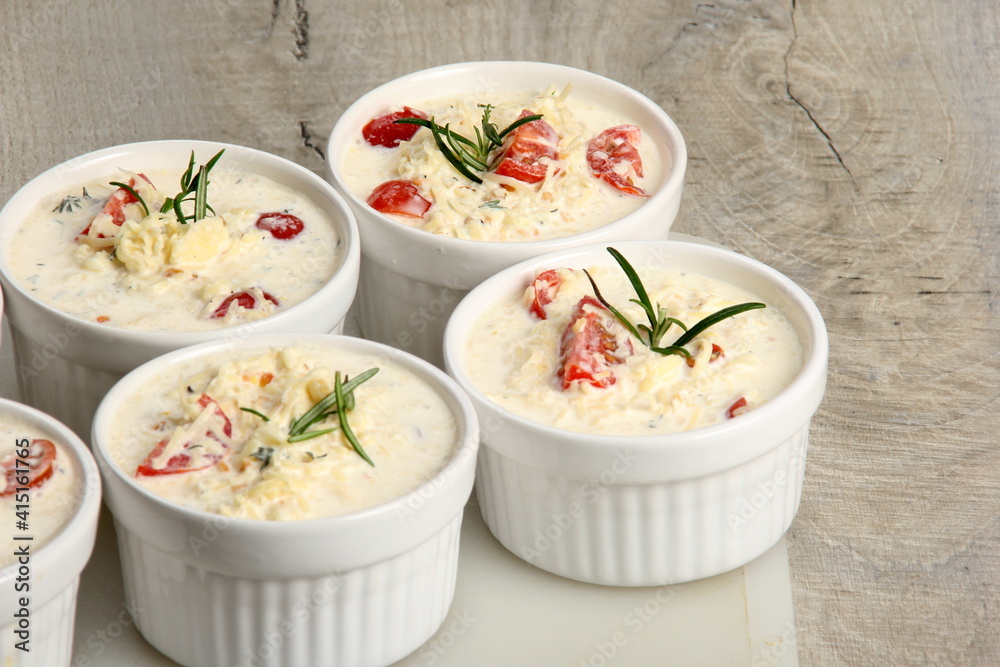 several dishes with casserole - sour cream, tomatoes and fish or other ingredients before baking. dishes with unroasted julienne several dishes with casserole - sour cream, tomatoes and fish or other ingredients before baking. dishes with unroasted julienne