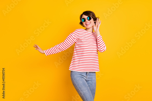 Photo of young beautiful happy smiling excited good mood girl in sunglasses dancing isolated on yellow color background
