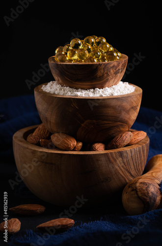 still life, healthy food concept, three bowls with almond nuts, powder and gelatin capsules in the form of a pyramid photo