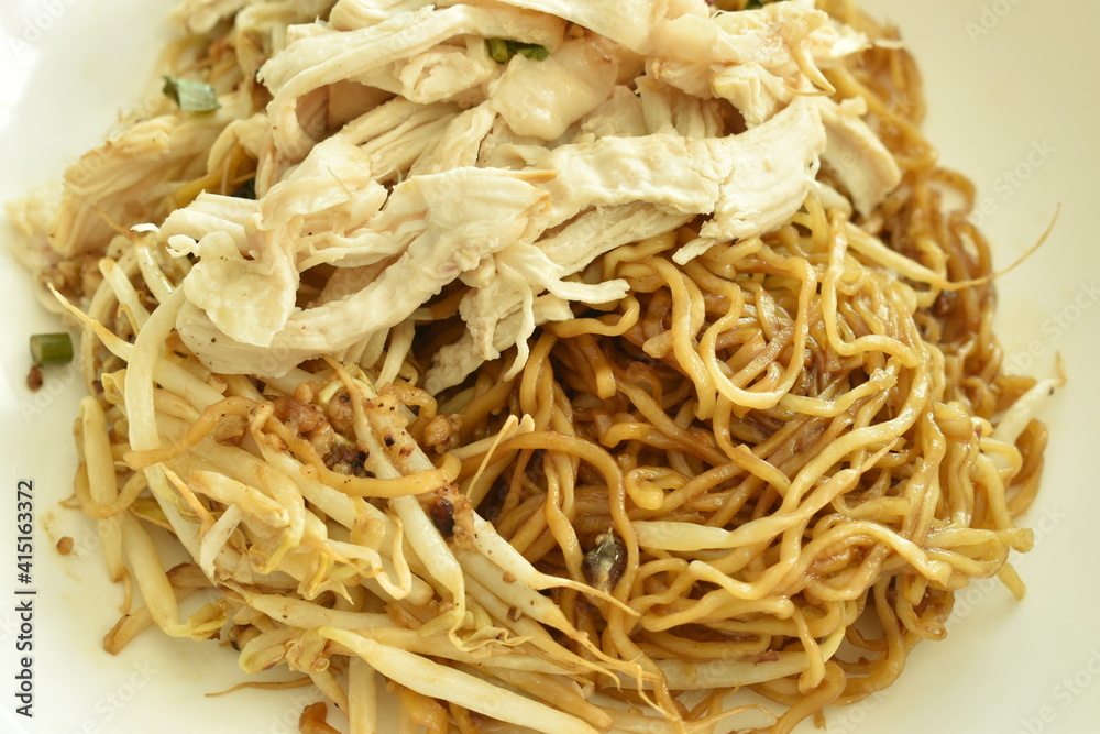 dry chinese yellow egg noodles dressing sweet black soy sauce topping slice boiled chicken on plate and soup bowl dry chinese yellow egg noodles dressing sweet black soy sauce topping slice boiled chicken on plate and soup bowl