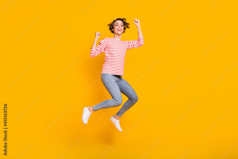 Full size photo of young happy positive excited crazy cheerful girl jumping in victory isolated on yellow color background