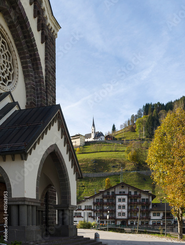 Traditional alpine architecture in Falcade alto in Val Biois, Chiesa di Ssn Sebastiano in the foreground. Italy. photo