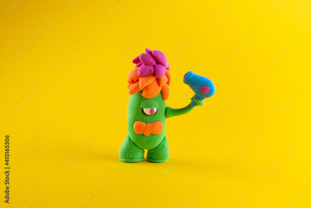 Funny clay figure fantasy alien drying his hair with hair dryer. Yellow background