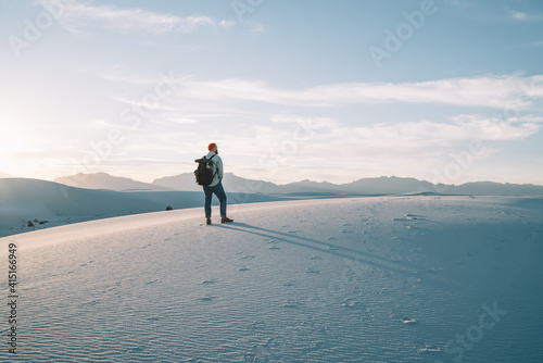 Unrecognizable man walking on sandy hill