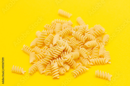 fusilli pasta macaroni on a yellow background.