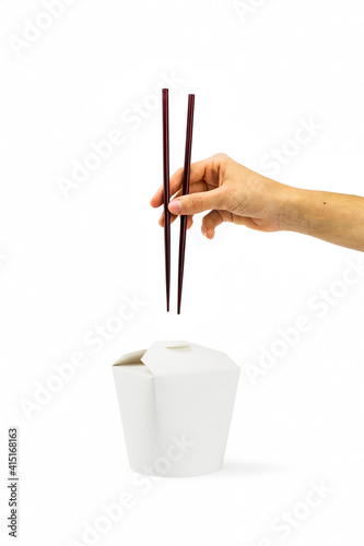 hand with chopsticks and cardboard food box on white background