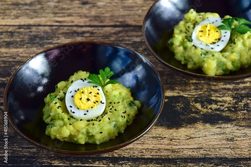 Mashed potato with peas and hard boiled egg garnish with parsley and sesame seeds 