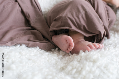 Cute little baby feet that lies on the bed at home. Happy motherhood 