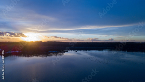 Aerial view of a beautiful and dramatic sunset over a forest lake reflected in the water  landscape drone shot. Blakheide  Beerse  Belgium. High quality photo