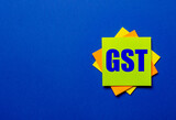 The words GST Goods and services tax is written on bright stickers on a blue background
