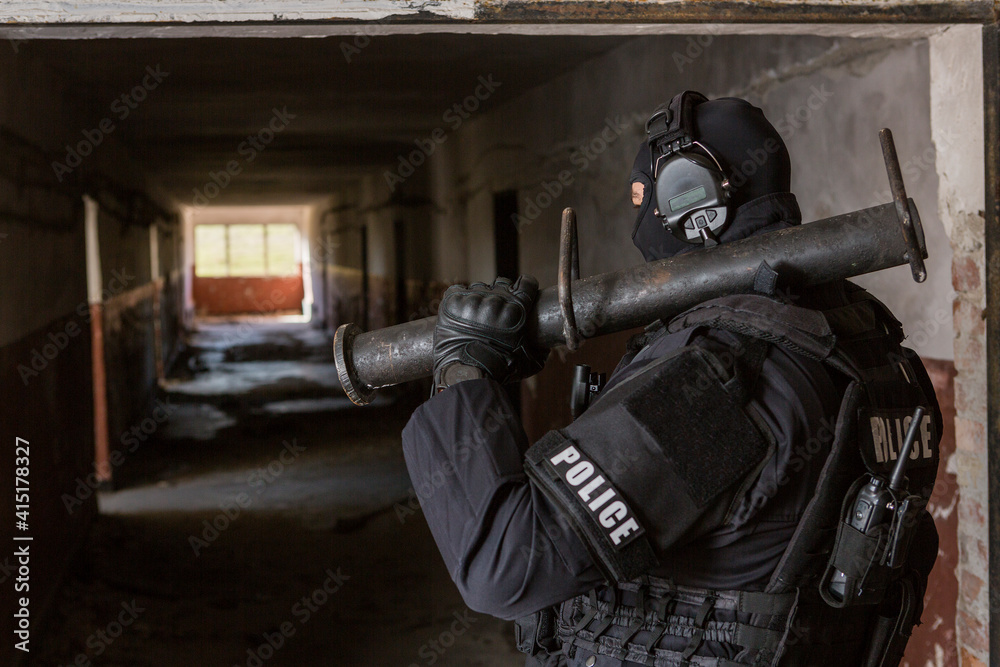 a special police officer holds a pistol, a sword and a grenade in his hands. a policeman in uniform poses in a ruined building. a special policeman in full combat gear ready for a mission and a task.