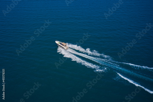 Top view of a white yacht sailing in the blue sea. Aerial view luxury motor boat. Drone view of a boat sailing across the blue clear waters. © Berg