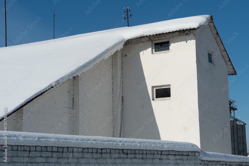 The roofs of the buildings are covered with snow and ice after a big snowfall. Huge icicles hang from the facades of buildings. The fall of icicles carries a danger to people's lives. The roofs of the buildings are covered with snow and ice after a big snowfall. Huge icicles hang from the facades of buildings. The fall of icicles carries a danger to people's lives.