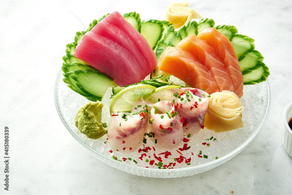 Classic Japanese sashimi set of raw salmon, eel and tuna with lime, cucumber on plate on a marble background. Close up, selective focus Classic Japanese sashimi set of raw salmon, eel and tuna with lime, cucumber on plate on a marble background. Close up, selective focus