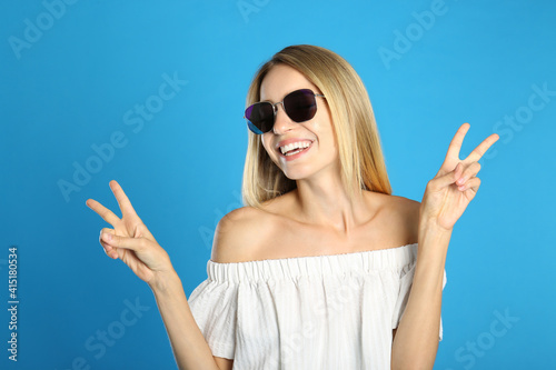 Beautiful woman in stylish sunglasses on light blue background