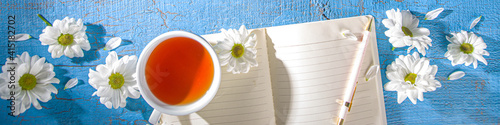 Chamomile flowers, notebook and tea background