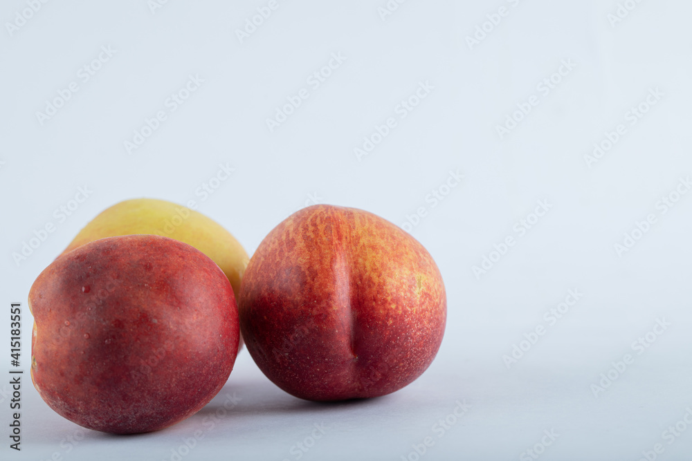 Ripe nectarines lie near a Cup of tea on a white background. Ripe nectarines lie near a Cup of tea on a white background.