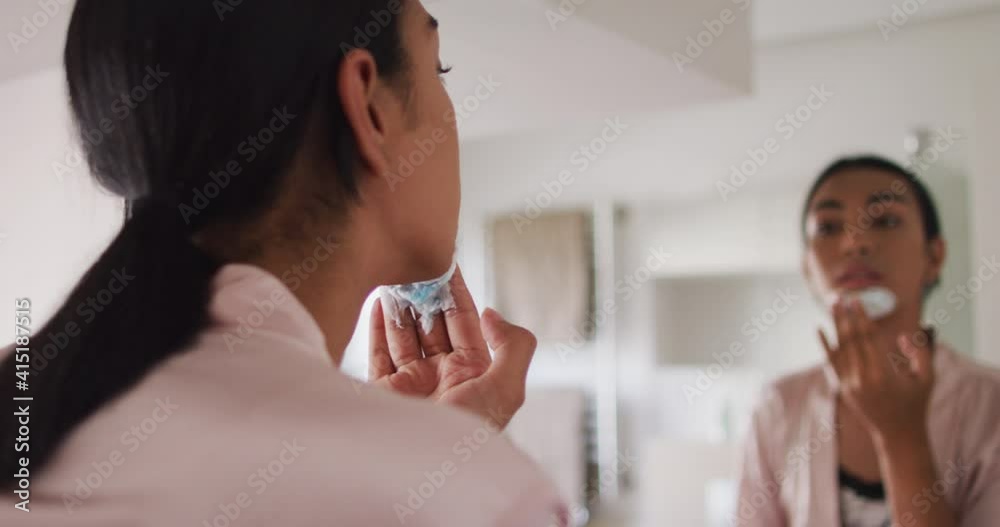 Mixed race gender fluid person standing in bathroom and putting shaving cream on Mixed race gender fluid person standing in bathroom and putting shaving cream on