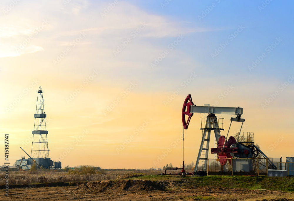 Crude oil pump jack at oilfield on atmospheric sunset backround. Fossil crude output and fuels oil production. Oil drill rig and drilling derrick. Global crude oil Prices, energy, petroleum demand Crude oil pump jack at oilfield on atmospheric sunset backround. Fossil crude output and fuels oil production. Oil drill rig and drilling derrick. Global crude oil Prices, energy, petroleum demand