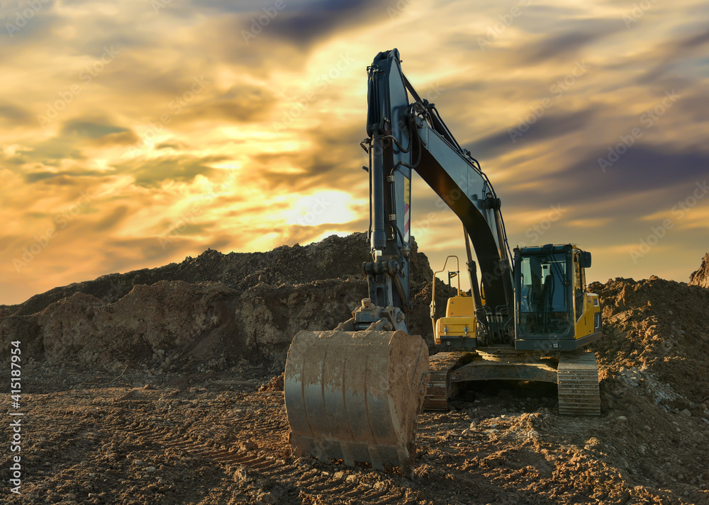 Excavator working on earthmoving at open pit mining on sunset