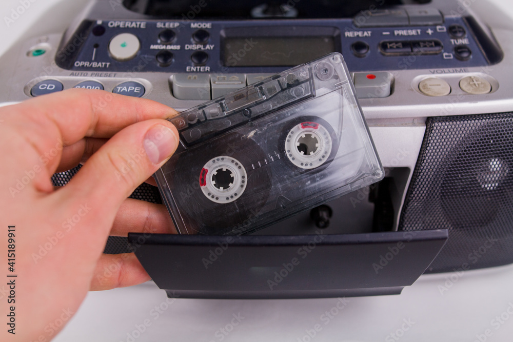 Obraz premium man inserts cassette into tape recorder on white background