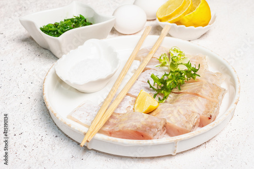 Pieces of raw hake, chukka salad, lemon wedge, fresh herbs, eggs as food preparation concept