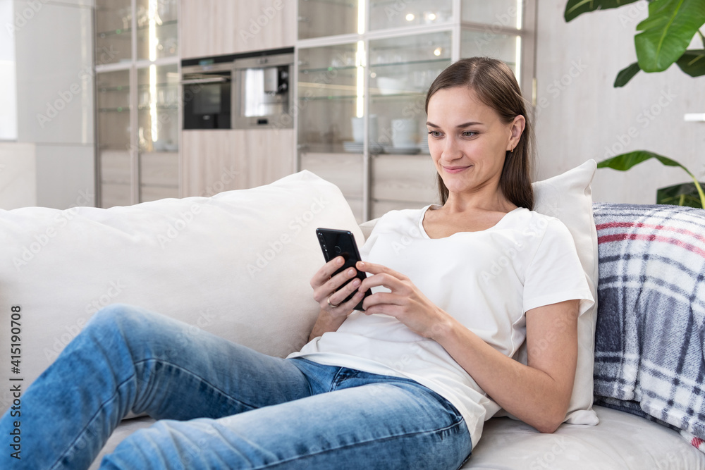 Woman uses smartphone on the couch Woman uses smartphone on the couch