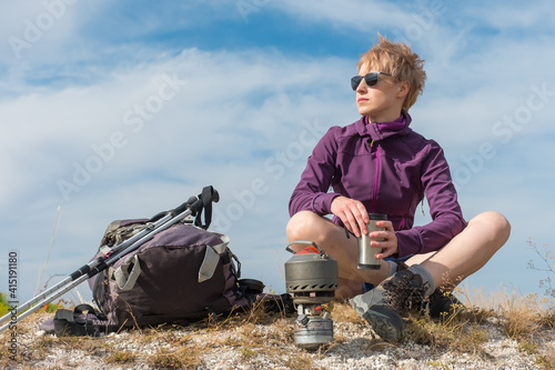 Girl in the mountains with a backpack and Scandinavian sticks.