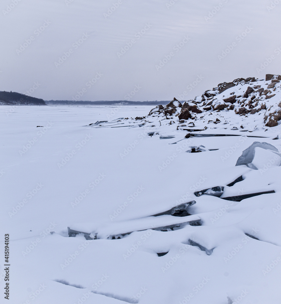 Fototapeta premium Ice perched on rock from a frozen snowy lake