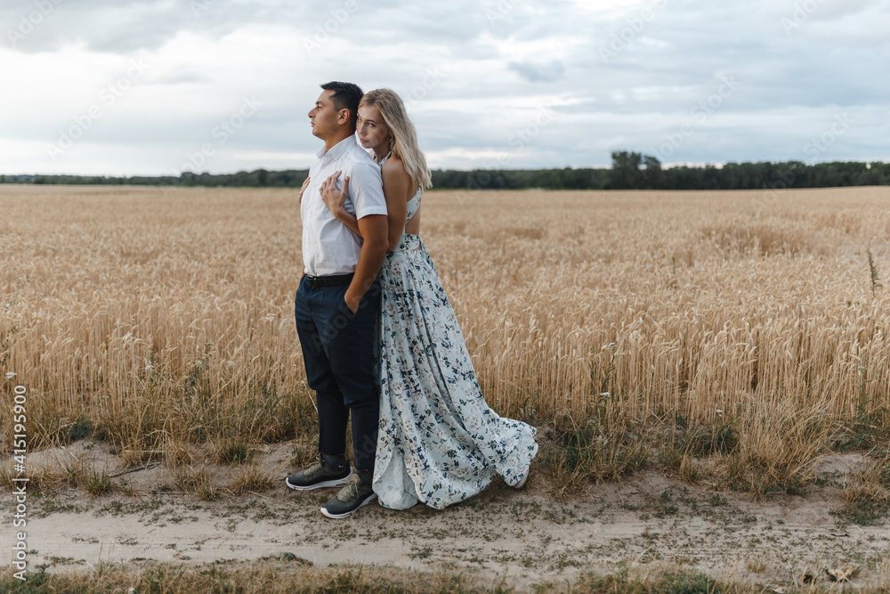 Happy couple look to the sunset in the wheat fild. Love story.