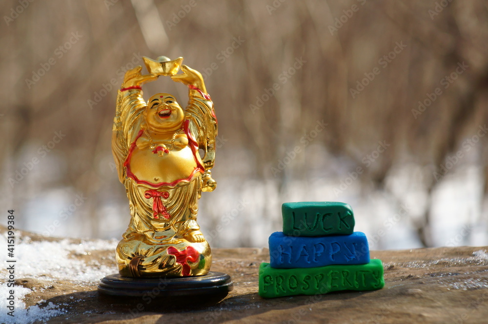 Fototapeta premium A statue of a smiling Buddha. Next to it is the inscription luck, happy, prosperity.