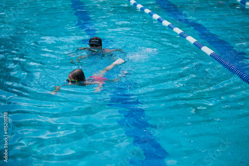 Little girl swimming during her swim lessons at the local outdoor pool in the summer