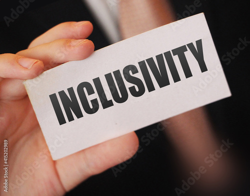 Inclusivity written on a card in businessman's hand. Diversity and tolerance in workplace business teamwork social wellfare concept photo