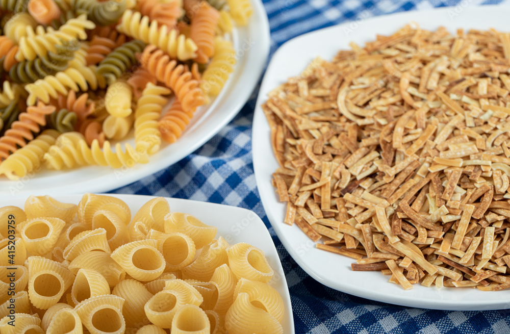 Variety of dry pasta on white plates