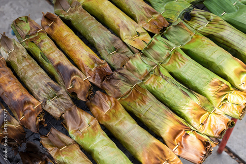 sticky rice banana stuff wrapped with banana leaves grilling on charcoal stove