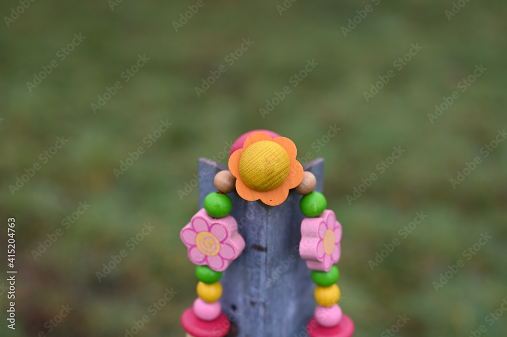 Naklejka premium buntes rosa orange schnullerband mit holzperlen über holzpfosten