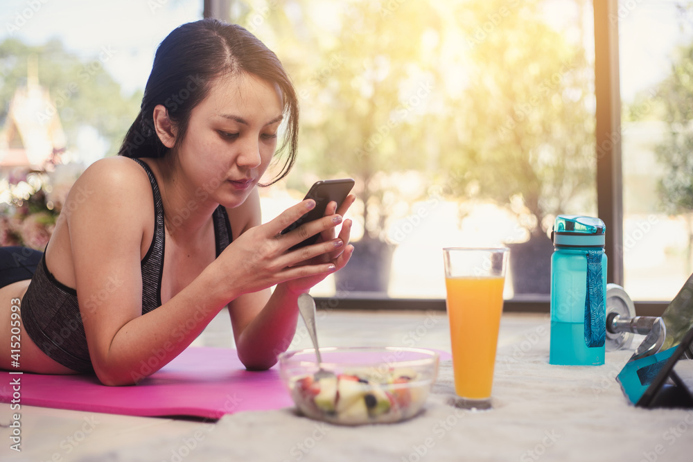 Healthy Asian woman diet eating salad fruit after exercise. Young woman in sportswear and use smartphone with bowl salad fruit. Healthy Asian woman diet eating salad fruit after exercise. Young woman in sportswear and use smartphone with bowl salad fruit.