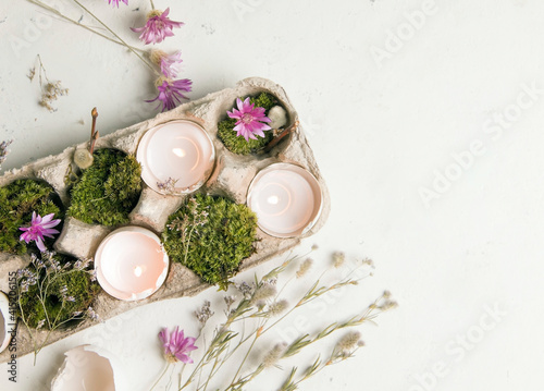 diy for easter. shells from eggs with candles on a white background with field flowers. copy space. close-up