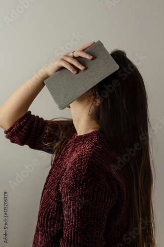 woman covering her face with a notebook