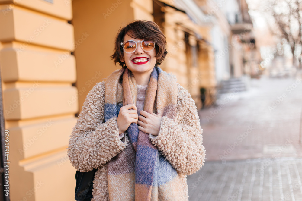 Happy short-haired woman enjoying cold day. Outdoor shot of charming brunette girl walking around city. Happy short-haired woman enjoying cold day. Outdoor shot of charming brunette girl walking around city.